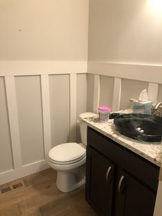 a bathroom with white walls and wood floors