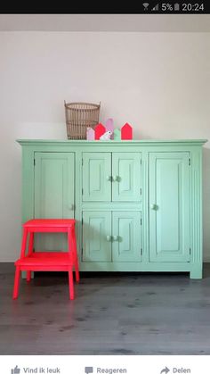 a red chair sitting next to a green cabinet