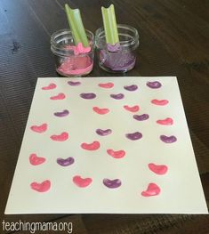 a paper with hearts on it next to two small jars filled with liquid and toothbrushes