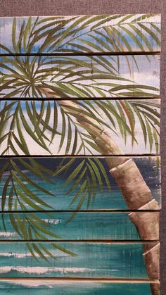 a palm tree painted on wooden planks with the ocean in the backround