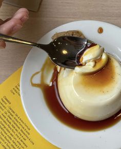 a spoon with some ice cream and sauce on it sitting on top of a white plate