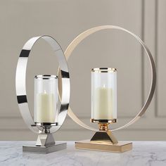 two candles are sitting on top of a marble table next to a circular candle holder