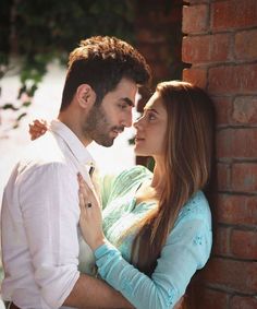 a man standing next to a woman near a brick wall