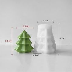 two plastic christmas trees sitting next to each other on a white surface with measurements for them