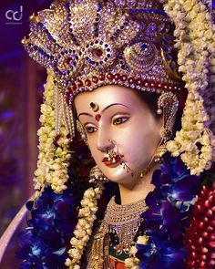 an elaborately decorated statue with flowers on it's head and face is shown