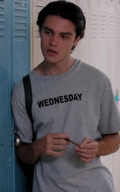 the young man is standing in front of lockers with his hand on his hip