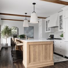 a large kitchen with wooden floors and white cabinets in the center, along with an island