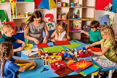 a group of children sitting around a table with art supplies