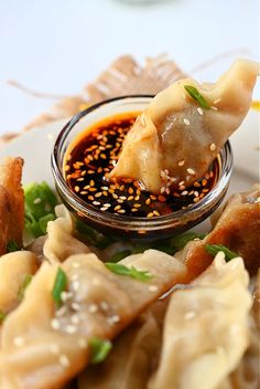 a plate topped with dumplings covered in sauce and garnished with sesame seeds