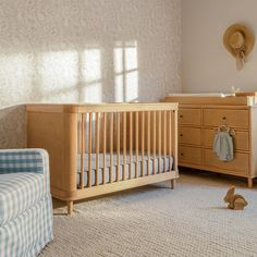 a baby's room with a crib, dresser and chair in it is shown