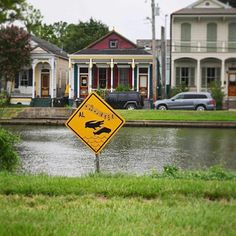 a street sign in the middle of a flooded area next to some houses and cars