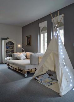 a teepee tent sitting in the middle of a living room next to a couch