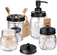 three jars with toothbrushes, soap dispenser and brush in them