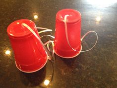 two red cups sitting on top of a table next to each other with white ribbons