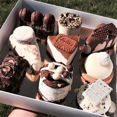 a box filled with lots of different types of cakes and pastries on top of green grass