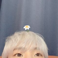 a person with white hair and a flower on top of their head