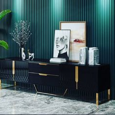 a black and gold sideboard in a room with green striped walls, plants and pictures on the wall