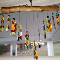 a wind chime hanging from a wooden beam with colorful glass pieces in the wind