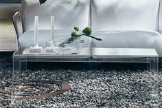 a glass coffee table sitting on top of a gravel covered floor next to a white couch