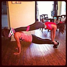 two women doing push ups on their stomachs in a living room with hardwood floors