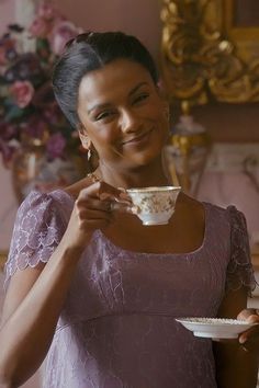 a woman in a purple dress holding a white bowl and plate with food on it