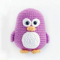 a crocheted purple bird with big eyes and a white eyeball in it's beak