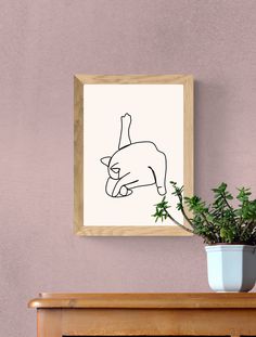 a potted plant sitting on top of a wooden table next to a framed drawing