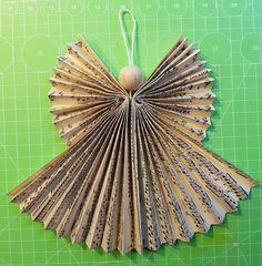 an ornament made out of book pages on a green cutting mat with scissors