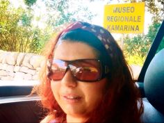 a woman wearing sunglasses sitting in the back seat of a car next to a sign