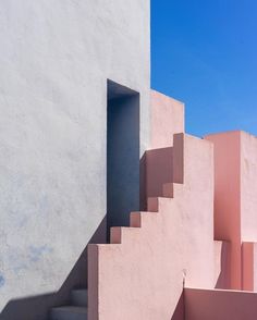 an open door on the side of a pink and white building with steps leading up to it