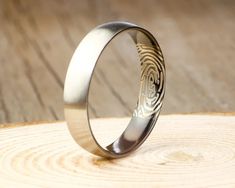 a wedding ring with fingerprints on it sitting on top of a piece of wood