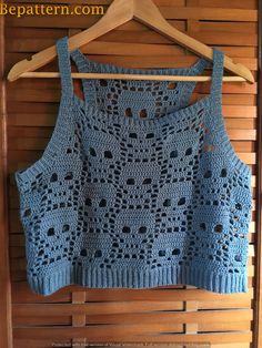 a blue crocheted sweater hanging on a wooden wall