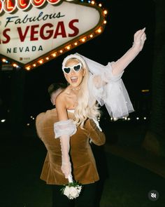 a woman dressed up as lady vegas in front of the las vegas sign