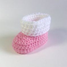 two crocheted pink and white baby booties sitting on top of each other