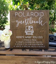 a wooden sign that says polaroid guestbook here's what you do, 2 snap a gorgeous photo 3 stick it in our guest book 4 write a special note & sing