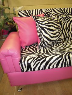 a pink couch with zebra print pillows on it and a pillow case in the middle