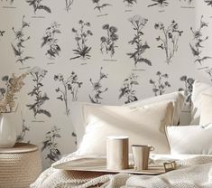 a bed with white sheets and pillows next to a wallpapered headboard in a bedroom