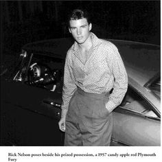 a man standing in front of a car with his hands on his hips