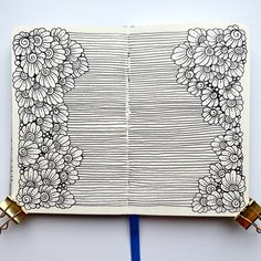 an open notebook with flowers and bells attached to it, sitting on a table next to a blue pen