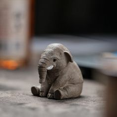 an elephant figurine sitting on the floor next to a bottle