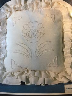 an embroidered pillow with ruffled edges on display