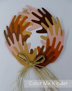 a paper wreath with brown and orange designs on it, tied to a white wall