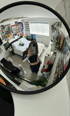 a woman taking a selfie in a mirror with her cell phone and some pictures on the wall