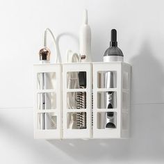 a white shelf with several compartments holding various hair brushes and other beauty products on it