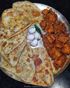 several flatbreads are arranged on a plate with onions and meat in the middle