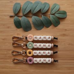 four name keychains with flowers and leaves on a wooden table next to each other