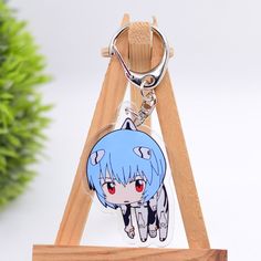 a key chain with an anime character on it sitting on a wooden stand next to a potted plant