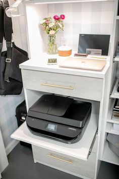 a printer is sitting on top of a drawer in a closet next to a purse