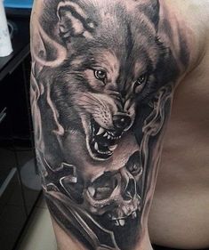 a man's arm with a wolf and skull tattoo on the left side of his arm