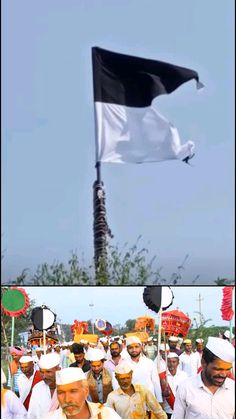 there are many people standing in front of a black and white flag that is flying